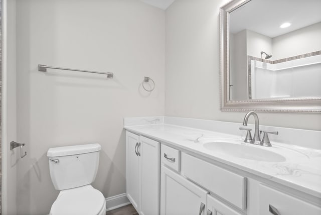 bathroom with walk in shower, vanity, and toilet