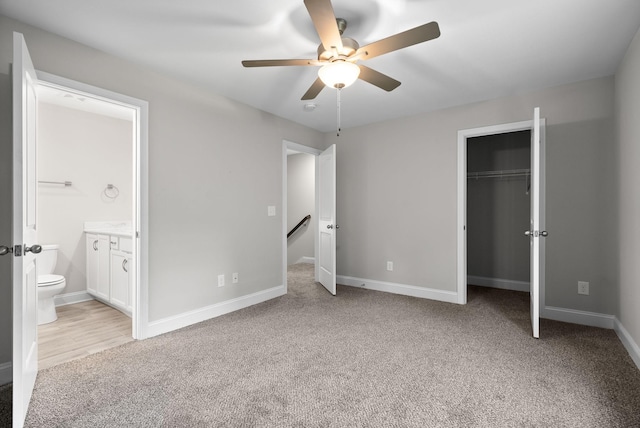 unfurnished bedroom with ceiling fan, ensuite bathroom, and light carpet