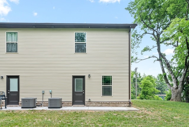 rear view of house featuring cooling unit and a yard