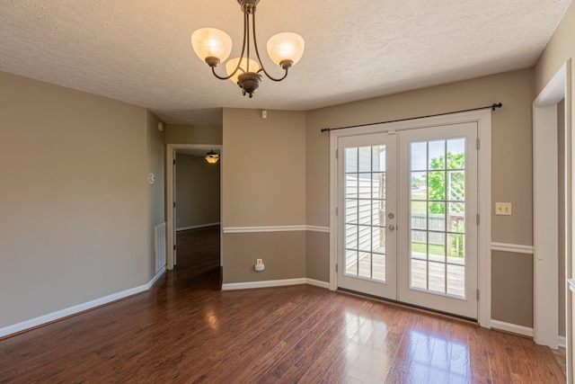 doorway to outside with dark wood-type flooring, a textured ceiling, a notable chandelier, and french doors