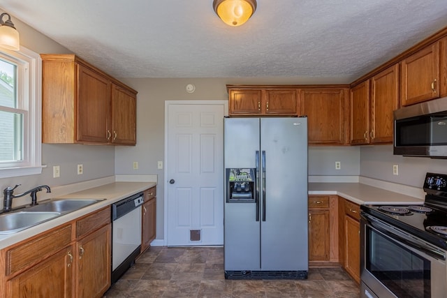 kitchen with appliances with stainless steel finishes, sink, and a textured ceiling