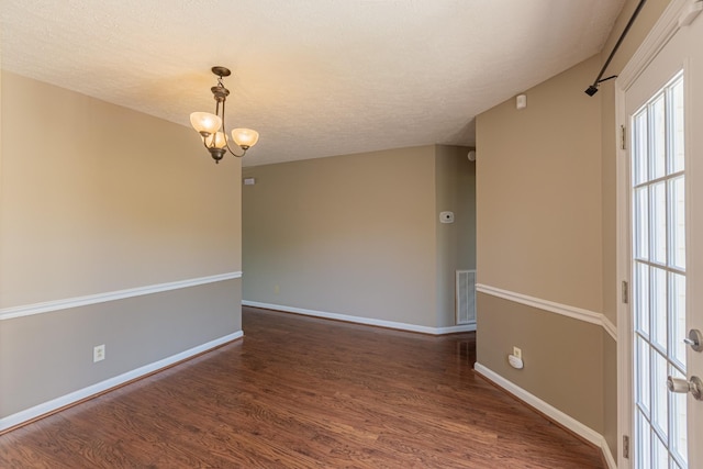 unfurnished room with a textured ceiling, dark wood-type flooring, and a chandelier