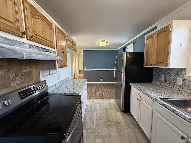 kitchen featuring white cabinets, ornamental molding, stainless steel appliances, and light hardwood / wood-style flooring