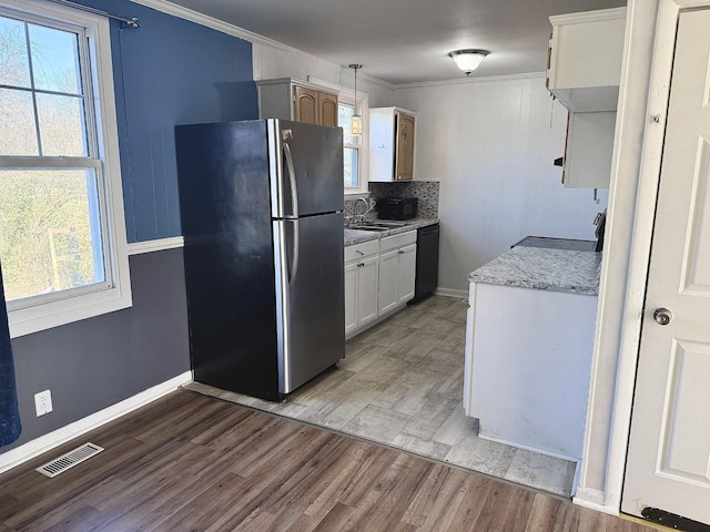 kitchen featuring ornamental molding, white cabinets, hardwood / wood-style floors, black dishwasher, and stainless steel refrigerator