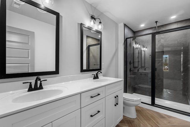 bathroom featuring toilet, vanity, a shower with door, and parquet flooring