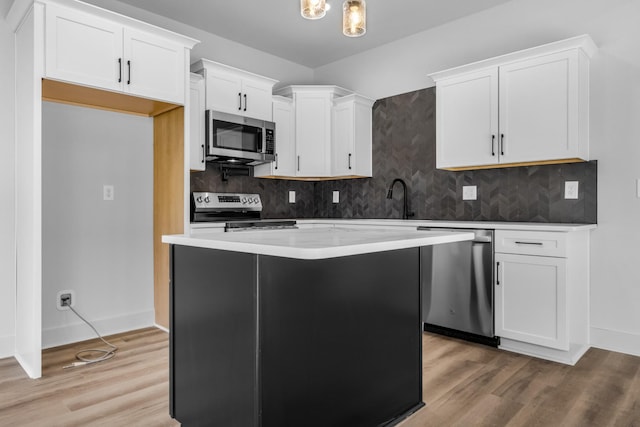 kitchen with light hardwood / wood-style floors, a center island, stainless steel appliances, and white cabinetry