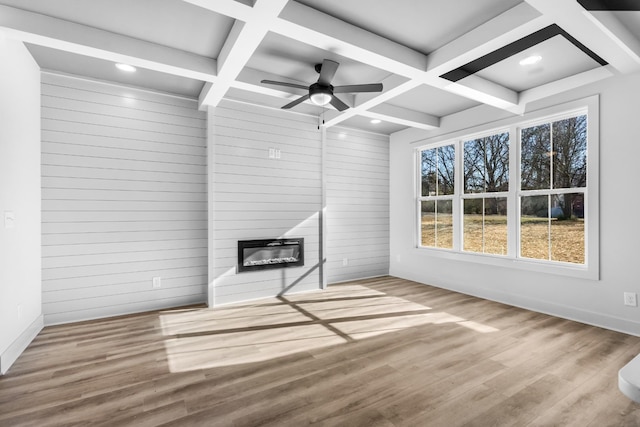 unfurnished living room with ceiling fan, beam ceiling, a fireplace, and coffered ceiling