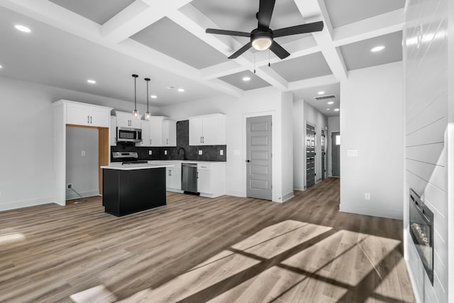 kitchen with pendant lighting, a kitchen island, coffered ceiling, white cabinetry, and stainless steel appliances