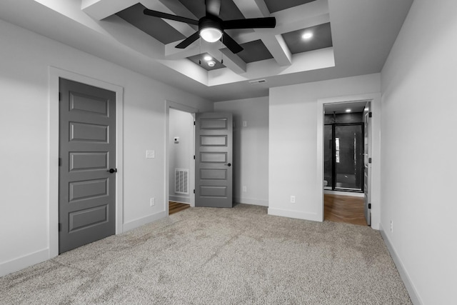 unfurnished bedroom with ceiling fan, light colored carpet, and coffered ceiling