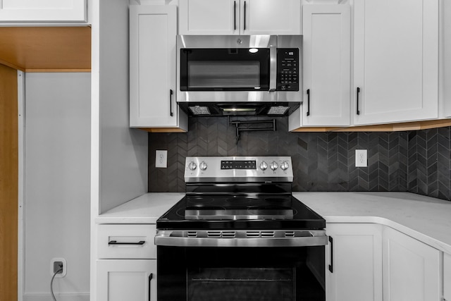 kitchen featuring stainless steel appliances, decorative backsplash, and white cabinetry