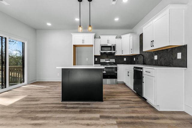 kitchen with hardwood / wood-style flooring, white cabinets, a center island, and stainless steel appliances