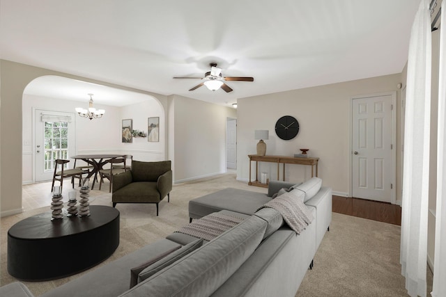 living room featuring light carpet and ceiling fan with notable chandelier