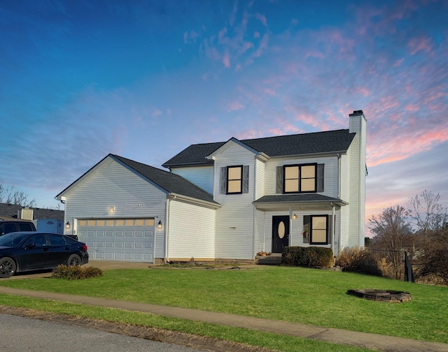 view of front facade featuring a chimney, concrete driveway, a lawn, and an attached garage