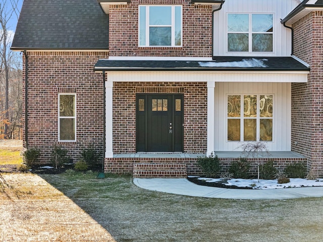 doorway to property with covered porch and a yard