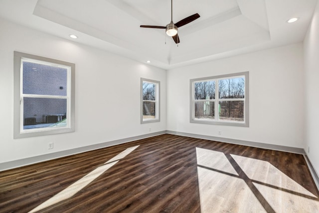 spare room featuring a raised ceiling, ceiling fan, and dark hardwood / wood-style flooring