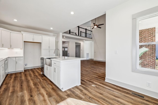 kitchen featuring white cabinets, sink, an island with sink, and a wealth of natural light