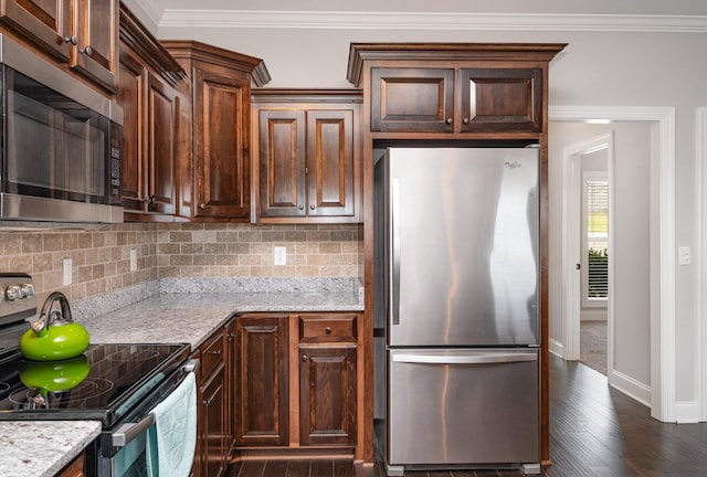 kitchen with tasteful backsplash, light stone countertops, ornamental molding, and appliances with stainless steel finishes