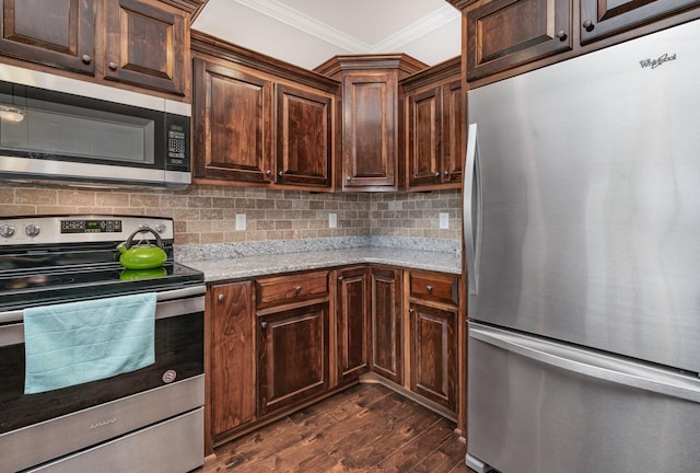 kitchen with dark wood-type flooring, light stone counters, backsplash, crown molding, and appliances with stainless steel finishes