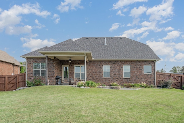 rear view of property with a lawn and ceiling fan