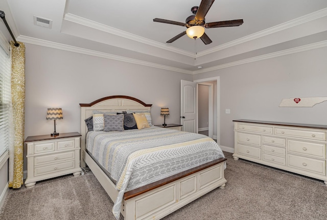 carpeted bedroom with a tray ceiling, ceiling fan, and ornamental molding