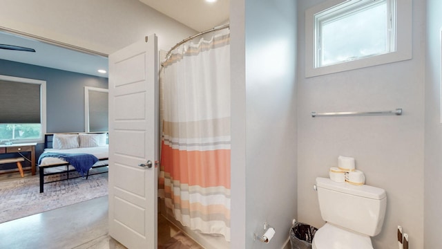 bathroom with concrete flooring, toilet, and walk in shower