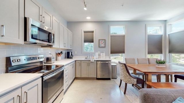 kitchen featuring backsplash, sink, stainless steel appliances, and plenty of natural light