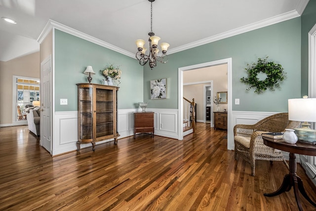 living area featuring dark hardwood / wood-style flooring, ornamental molding, and a chandelier