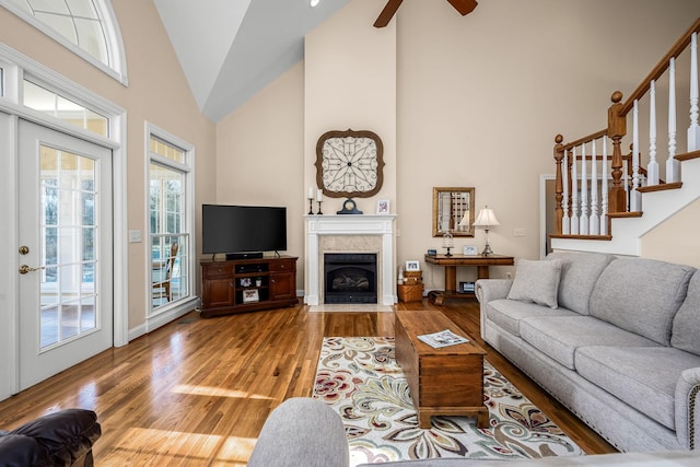 living room with ceiling fan, hardwood / wood-style flooring, a tile fireplace, and a healthy amount of sunlight