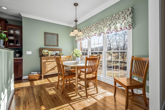 dining area featuring a notable chandelier, ornamental molding, and hardwood / wood-style floors