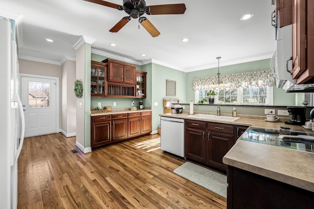 kitchen with sink, crown molding, wood-type flooring, decorative light fixtures, and stainless steel dishwasher