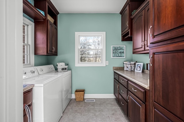 clothes washing area with cabinets, light tile patterned flooring, and washing machine and clothes dryer