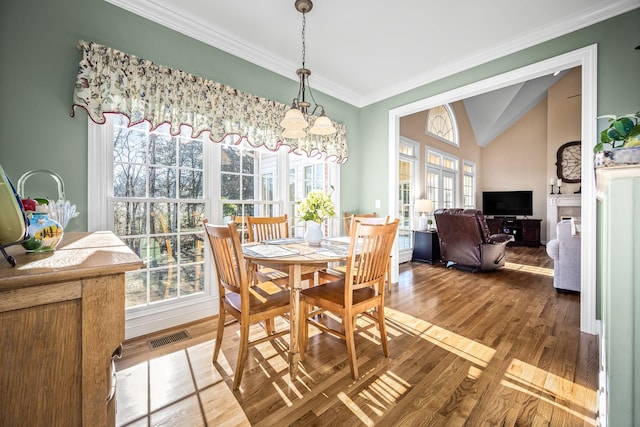 dining space with a notable chandelier, crown molding, vaulted ceiling, and hardwood / wood-style floors