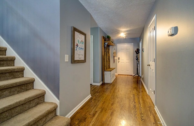 hallway with a textured ceiling and hardwood / wood-style flooring