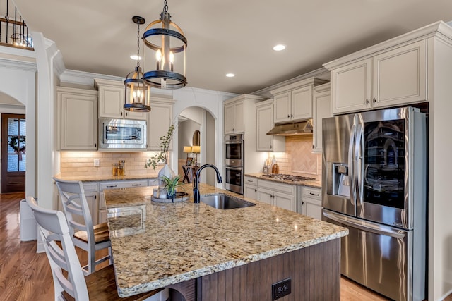 kitchen with a center island with sink, hanging light fixtures, appliances with stainless steel finishes, and a breakfast bar area