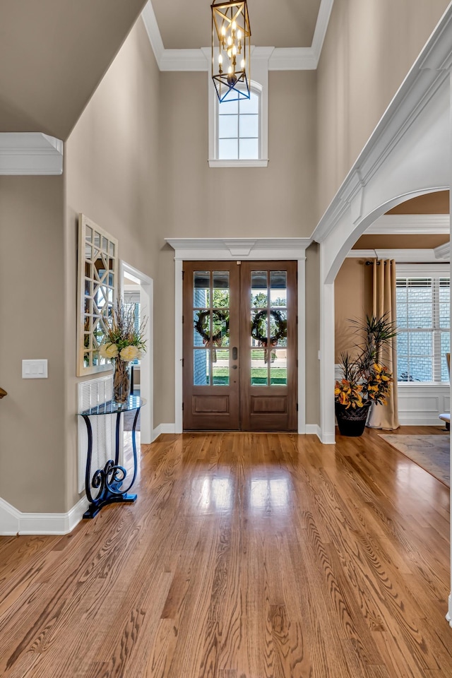 foyer featuring hardwood / wood-style floors, a notable chandelier, a healthy amount of sunlight, and french doors