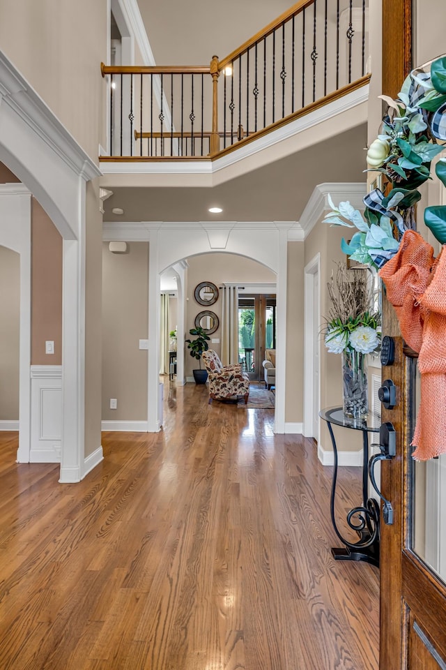 entryway with hardwood / wood-style floors, a towering ceiling, and ornamental molding