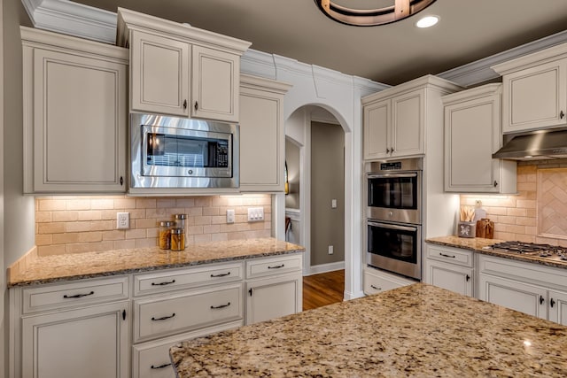 kitchen featuring backsplash, light stone counters, white cabinets, and appliances with stainless steel finishes