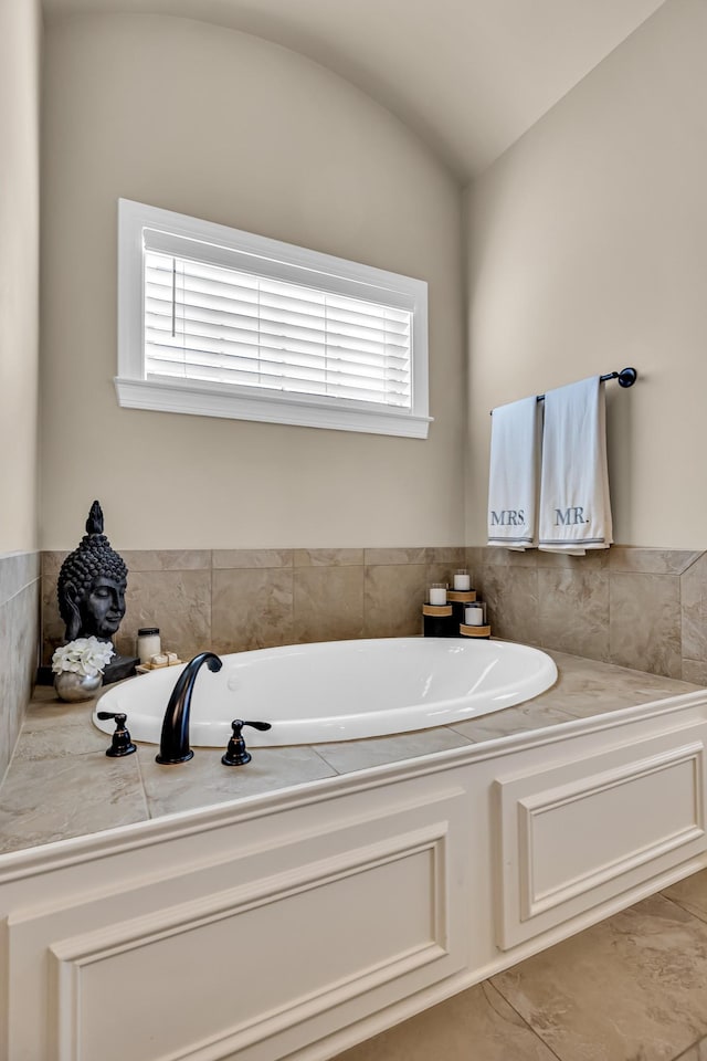 bathroom with tile patterned flooring, a washtub, a healthy amount of sunlight, and vaulted ceiling