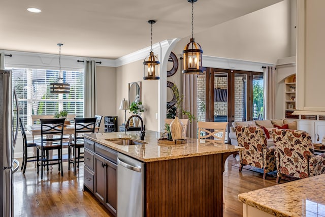 kitchen featuring appliances with stainless steel finishes, a kitchen island with sink, sink, pendant lighting, and a chandelier