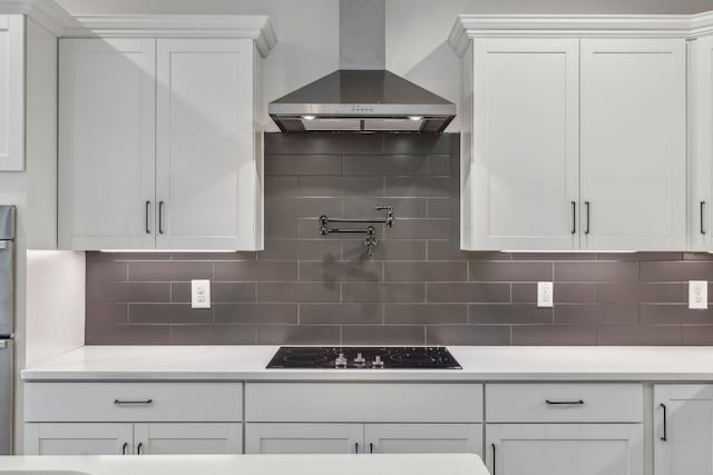 kitchen featuring wall chimney exhaust hood, backsplash, double oven, black electric stovetop, and white cabinets