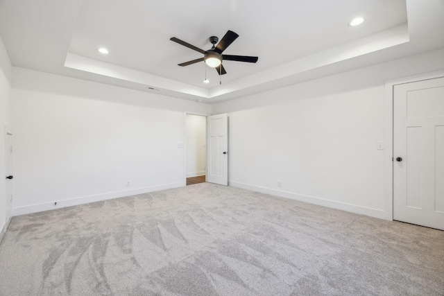 carpeted spare room featuring ceiling fan and a raised ceiling