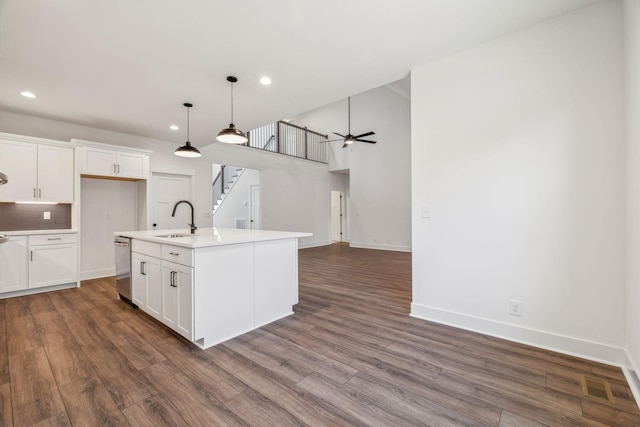 kitchen with ceiling fan, sink, decorative light fixtures, white cabinets, and an island with sink