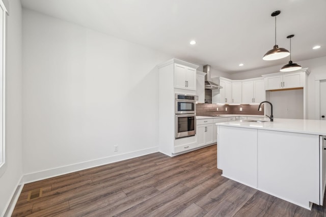 kitchen with white cabinets, sink, wall chimney exhaust hood, and pendant lighting