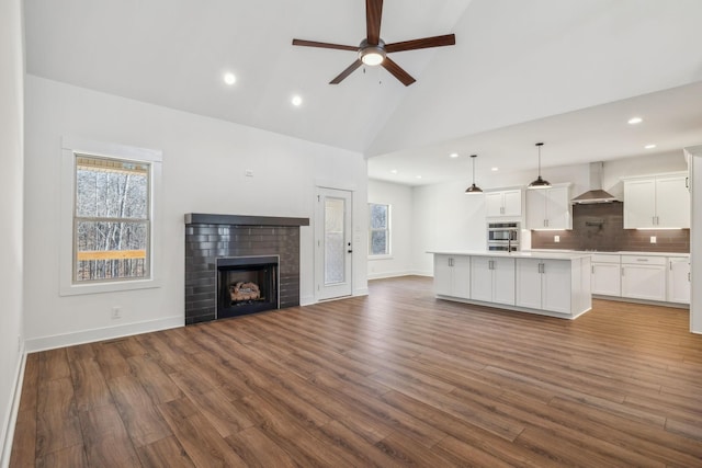 unfurnished living room with dark hardwood / wood-style flooring, ceiling fan, a fireplace, and high vaulted ceiling