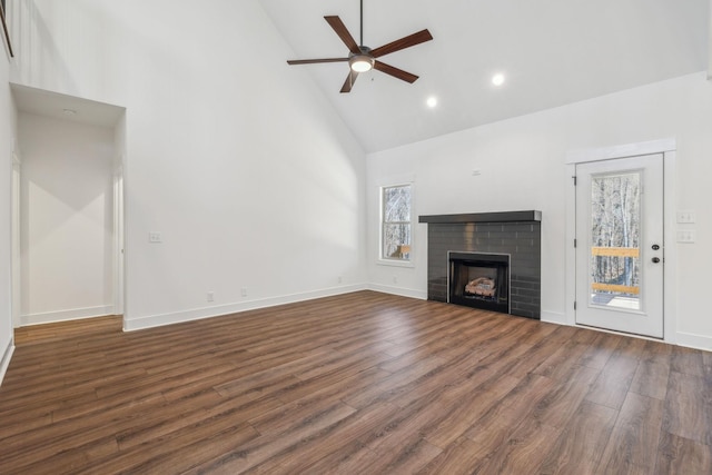 unfurnished living room with a brick fireplace, dark hardwood / wood-style floors, high vaulted ceiling, and ceiling fan