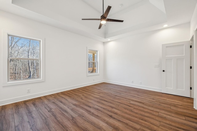 unfurnished room featuring dark hardwood / wood-style flooring, a tray ceiling, and ceiling fan