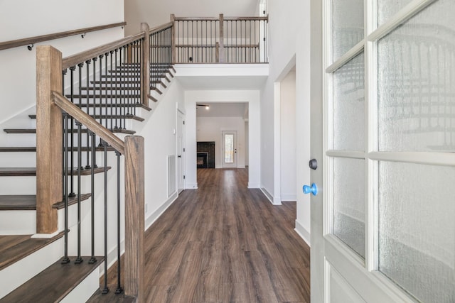 entrance foyer featuring a towering ceiling and dark wood-type flooring