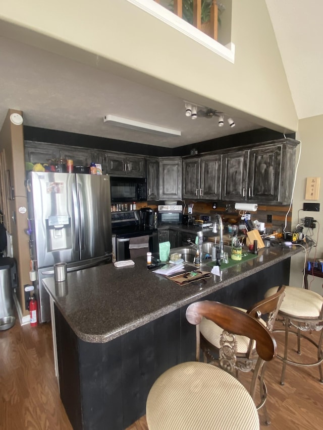 kitchen featuring kitchen peninsula, stainless steel appliances, sink, high vaulted ceiling, and dark hardwood / wood-style floors