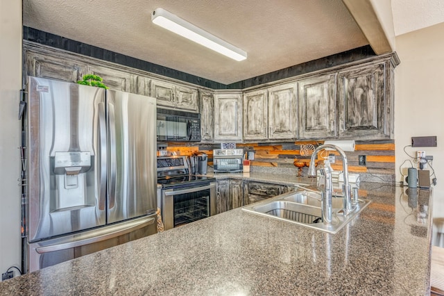 kitchen with kitchen peninsula, sink, a textured ceiling, and appliances with stainless steel finishes