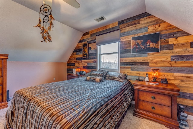 bedroom with carpet flooring, ceiling fan, and wood walls